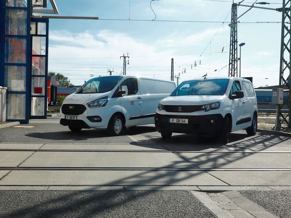 Zwei Funktionsfahrzeuge von DB Connect vor Gleisen. 
