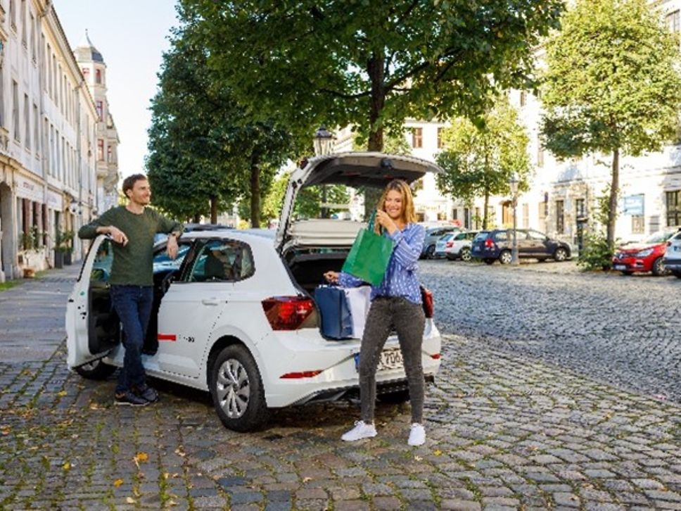 Personen vor einem Flinkster-Mietauto.