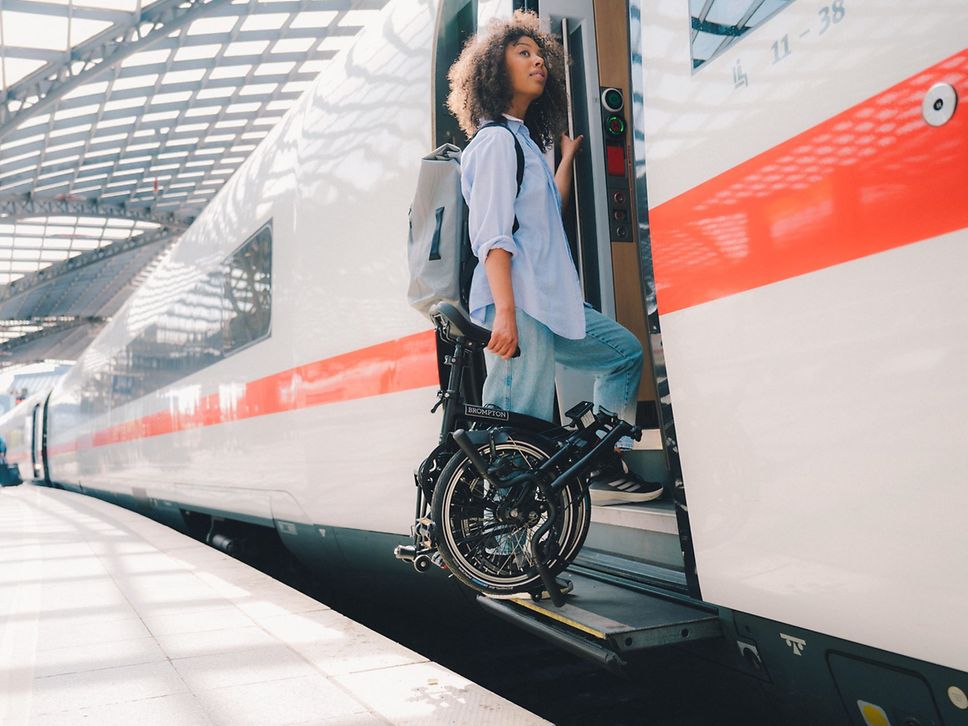 Frau steigt mit Brompton in einen ICE ein.
