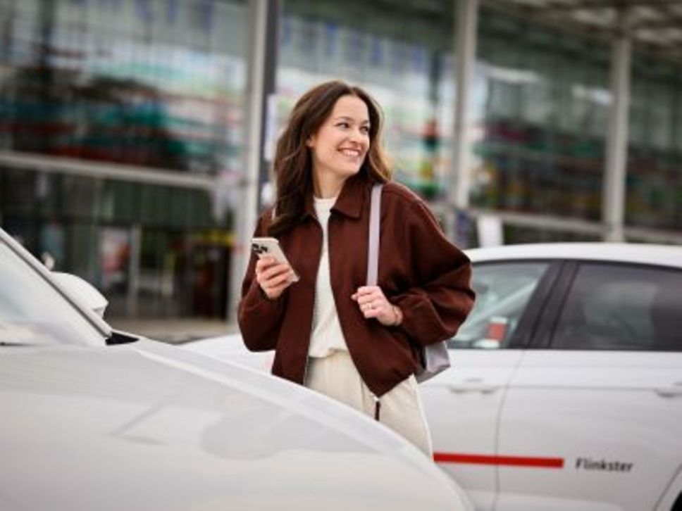 Eine Frau vor einem Flinkster-Fahrzeug.